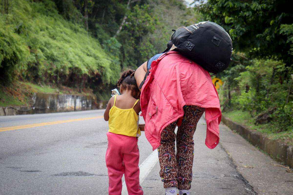 Mujer y su hija caminando por una carretera