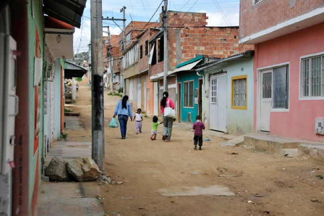 Mujeres y niños caminando en una calle sin pavimentar